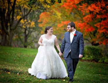 bride and groom hand in hand in front of fall colors