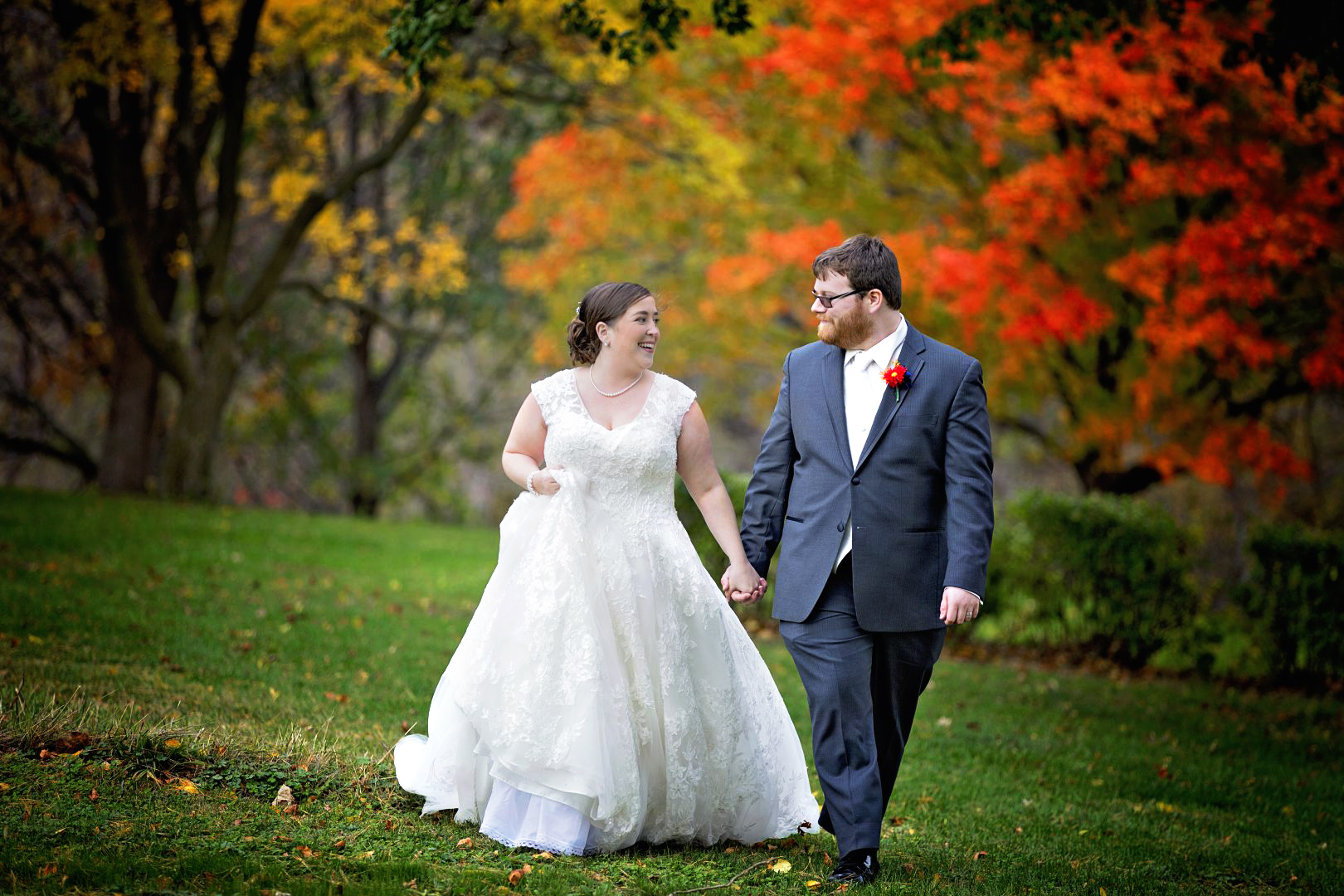 bride and groom hand in hand in front of fall colors
