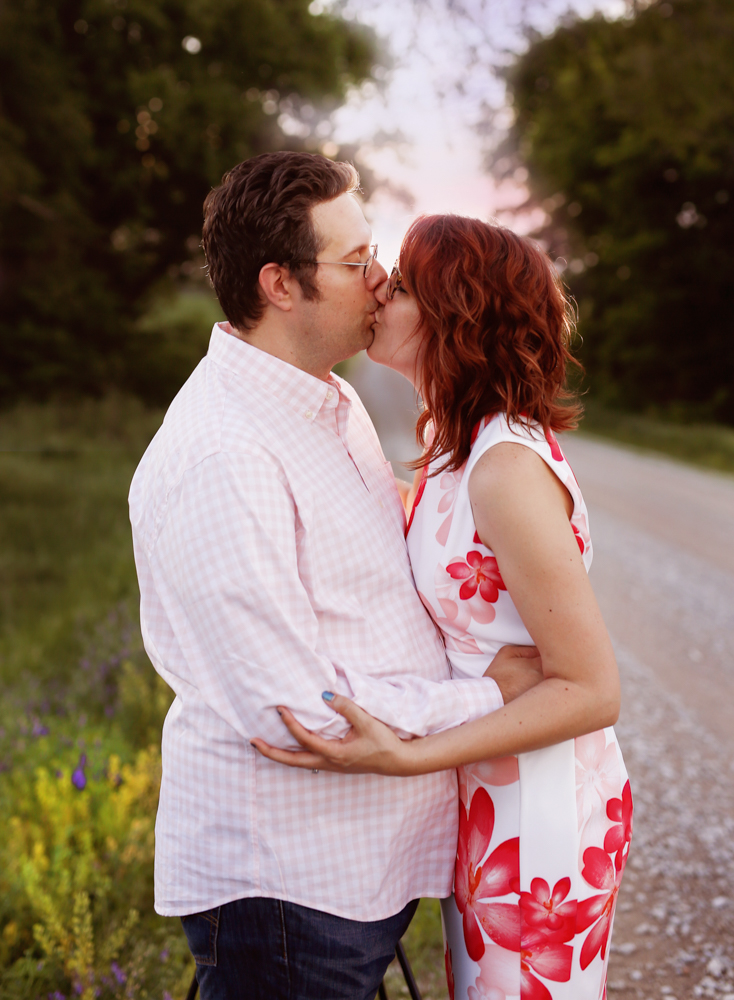engaged couple kisses along a country road