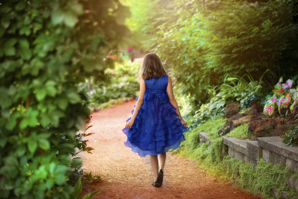 Girl in blue dress walks down path