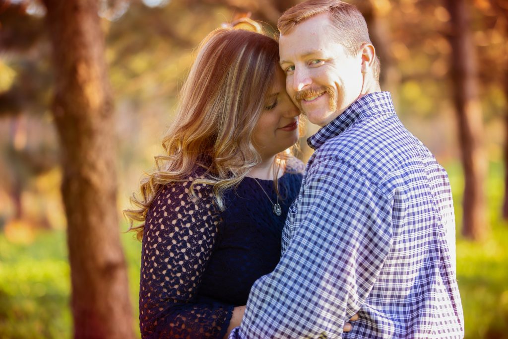 engaged couple share a moment as man looks at camera