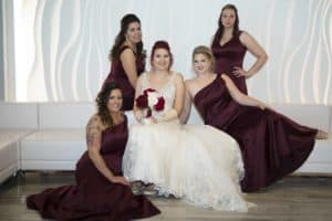 Bride sits on white sofa with her bridesmaids at Suite One Eleven