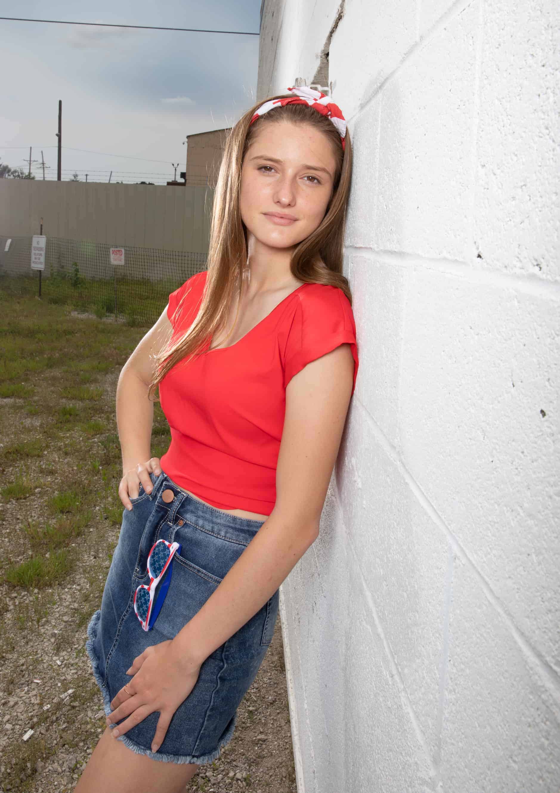 Girl leans against white wall
