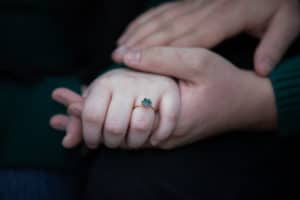 man holds woman's hand, showing her ring