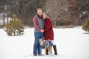 couple poses with their dog in teh snow