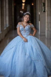 Leslie stands in a hallway wearing her quinceanera dress