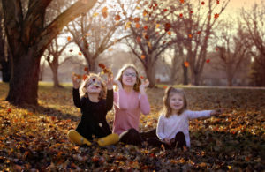 Three sisters throw leaves in the air