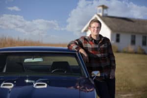 senior boy poses with his blue car