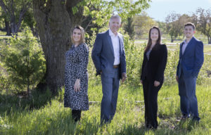 Four co-workers stand by a tree