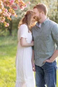 engaged couple stand under a flowering tree