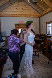 bride gets help buttoning her dress