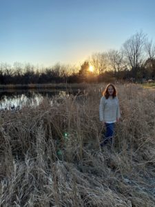 Lori stands in a field at sunset