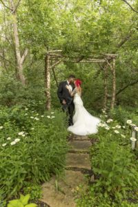 bride and groom kiss under an arch
