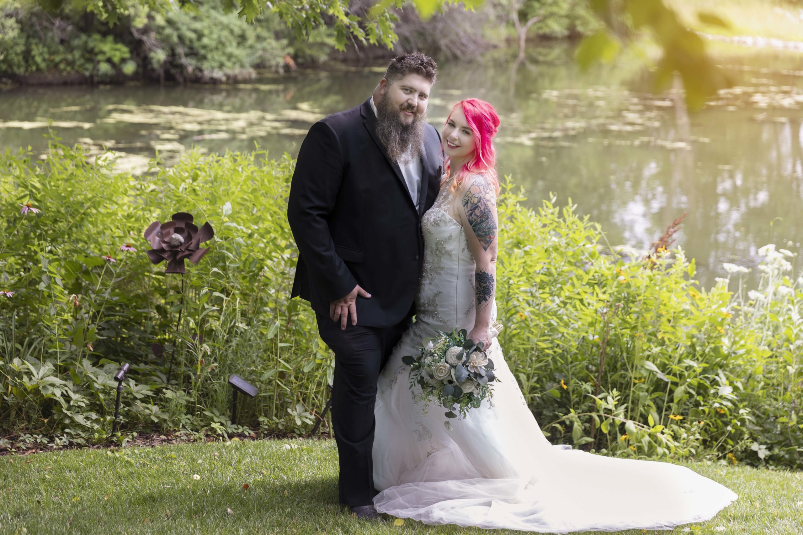 bride and groom in front of pond