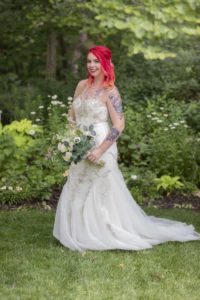 Bride poses with her bouquet in the greenery