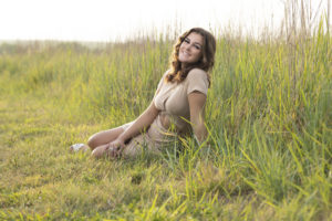 Full body shot of Leah sitting in tall grass