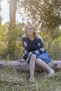 Emmie sits on a log during her senior session