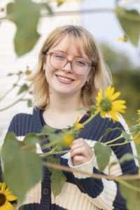 Emmie stands by sunflowers