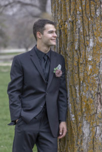 groom stands by tree and looks at side