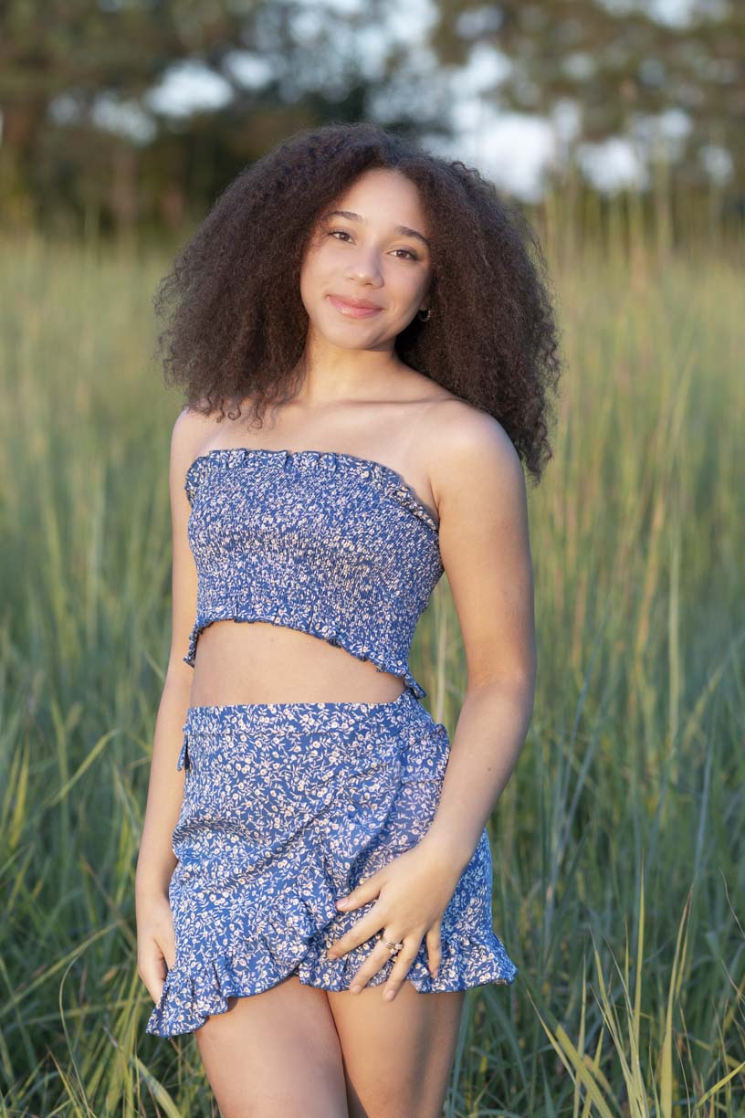 girl at her senior photo shoot stands in tall grass