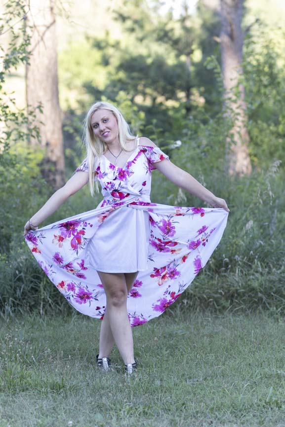 blond senior shows her floral dress at her senior photo shoot