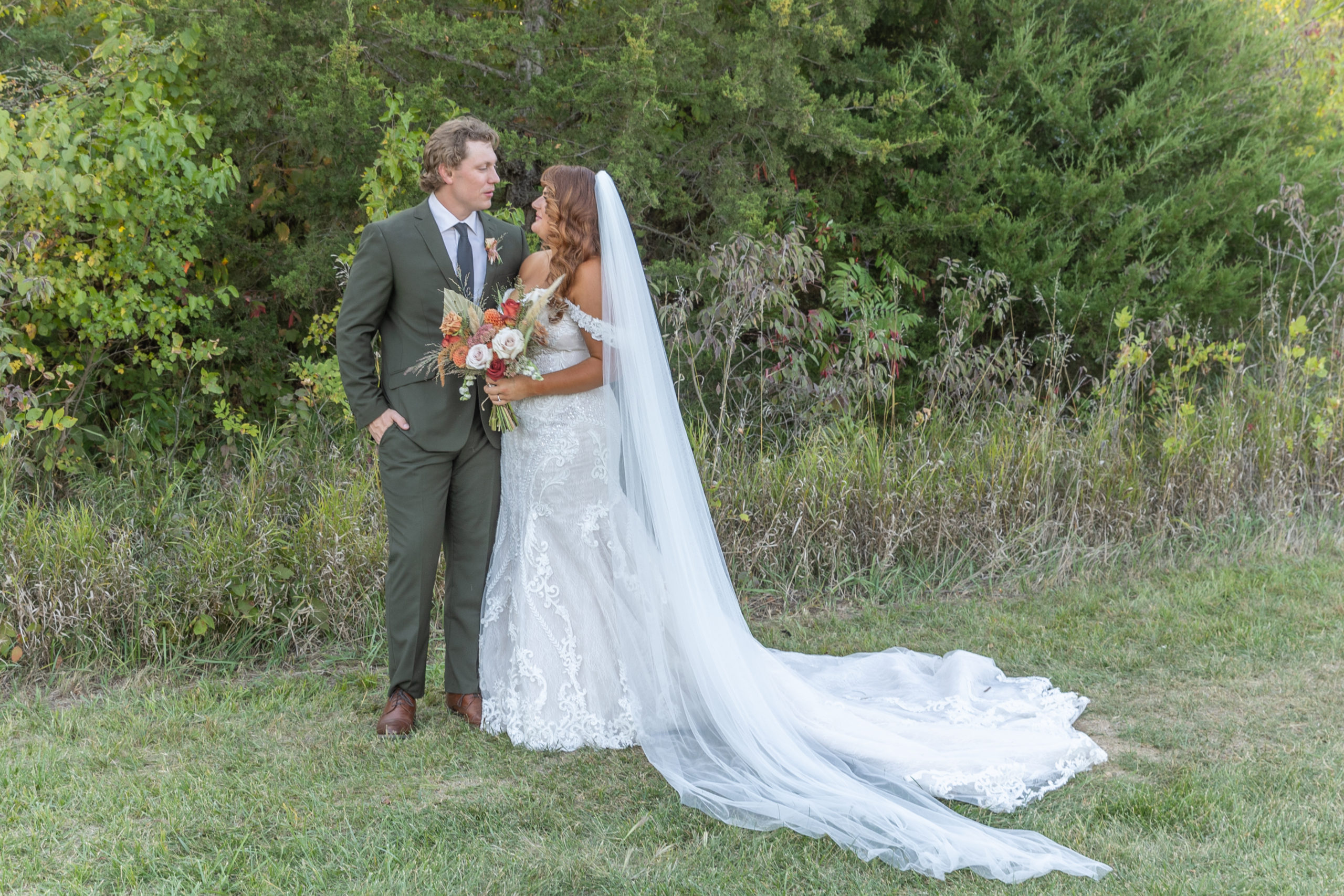 bride and groom in greenery looking at each other Slattery Vintage Estates Wedding