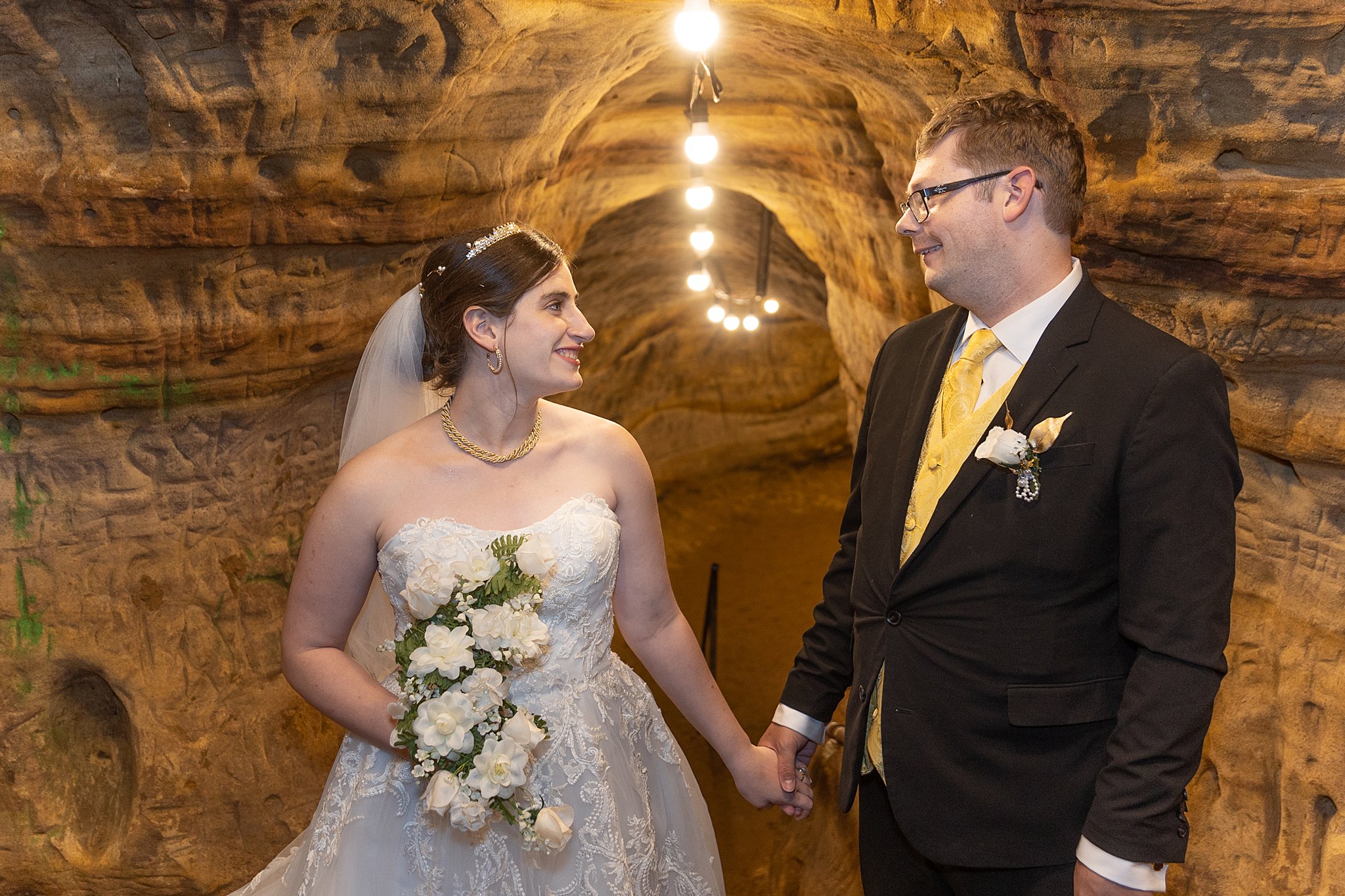 Newlywed couple holds hands looking at each other in a brrown cave robbers cave lincoln ne