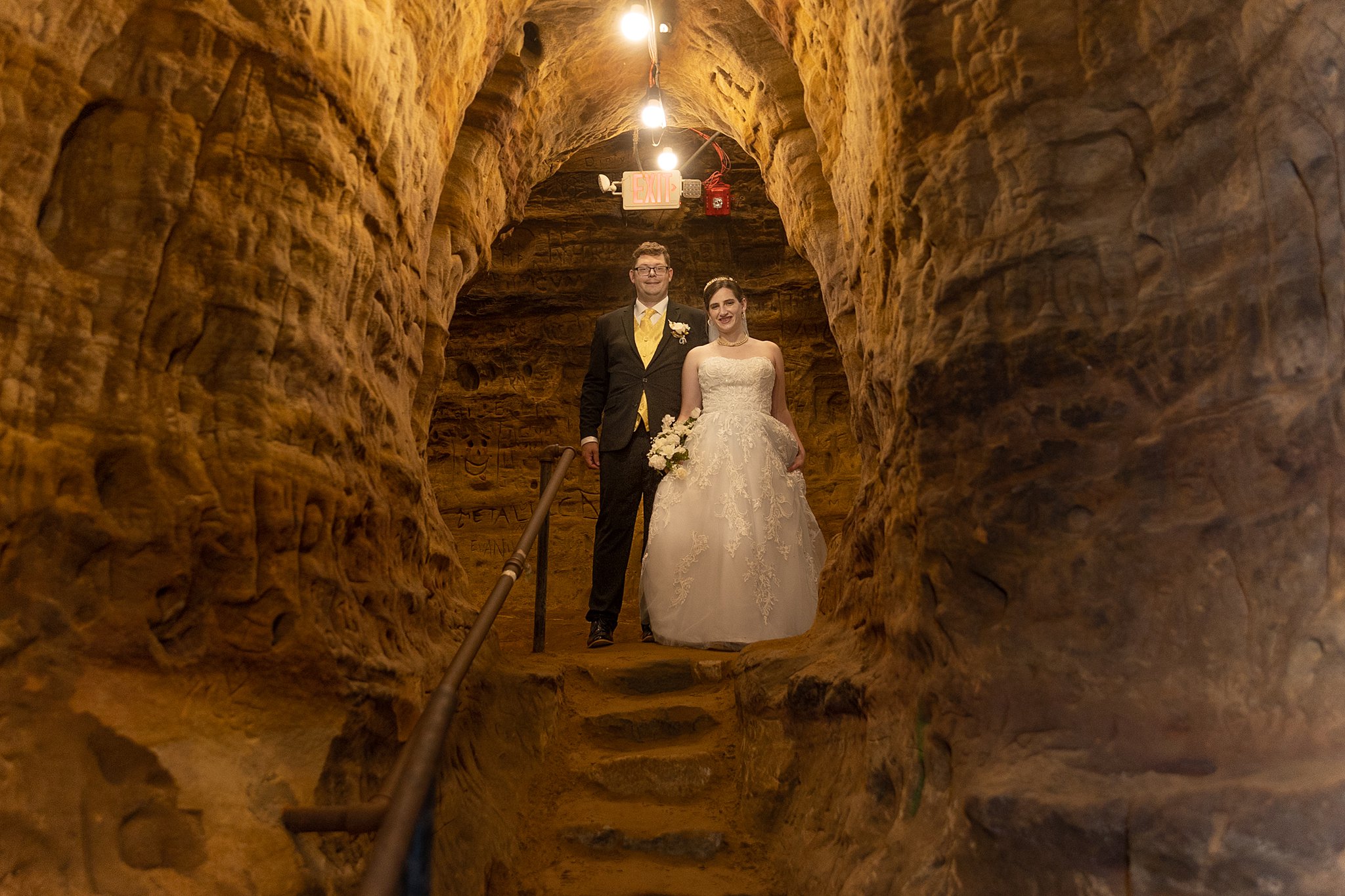 Bride and groom stand at the top of carved stairs in a cave robbers cave lincoln ne