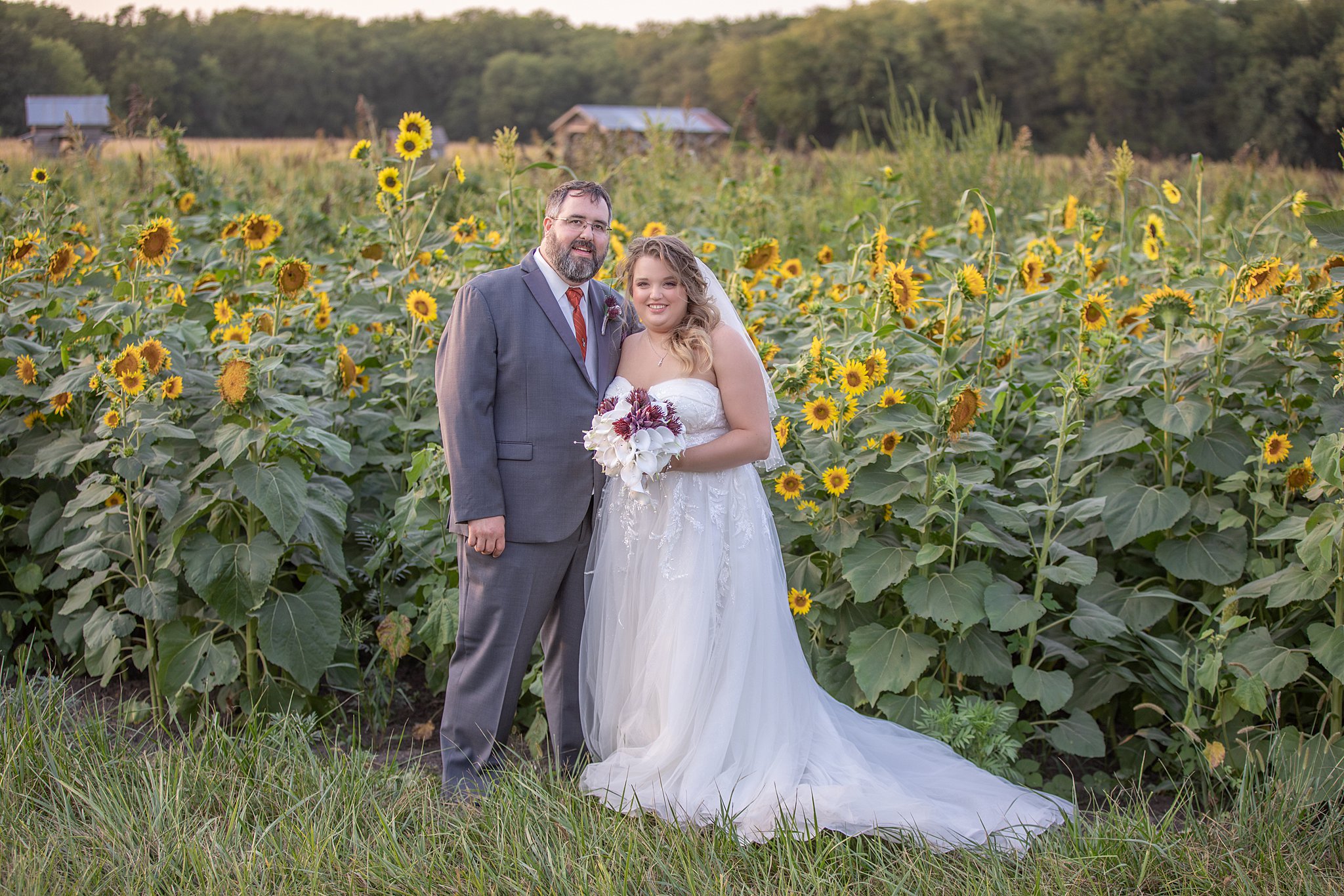 newlyweds stand in front of a sunflower field roca berry farm wedding