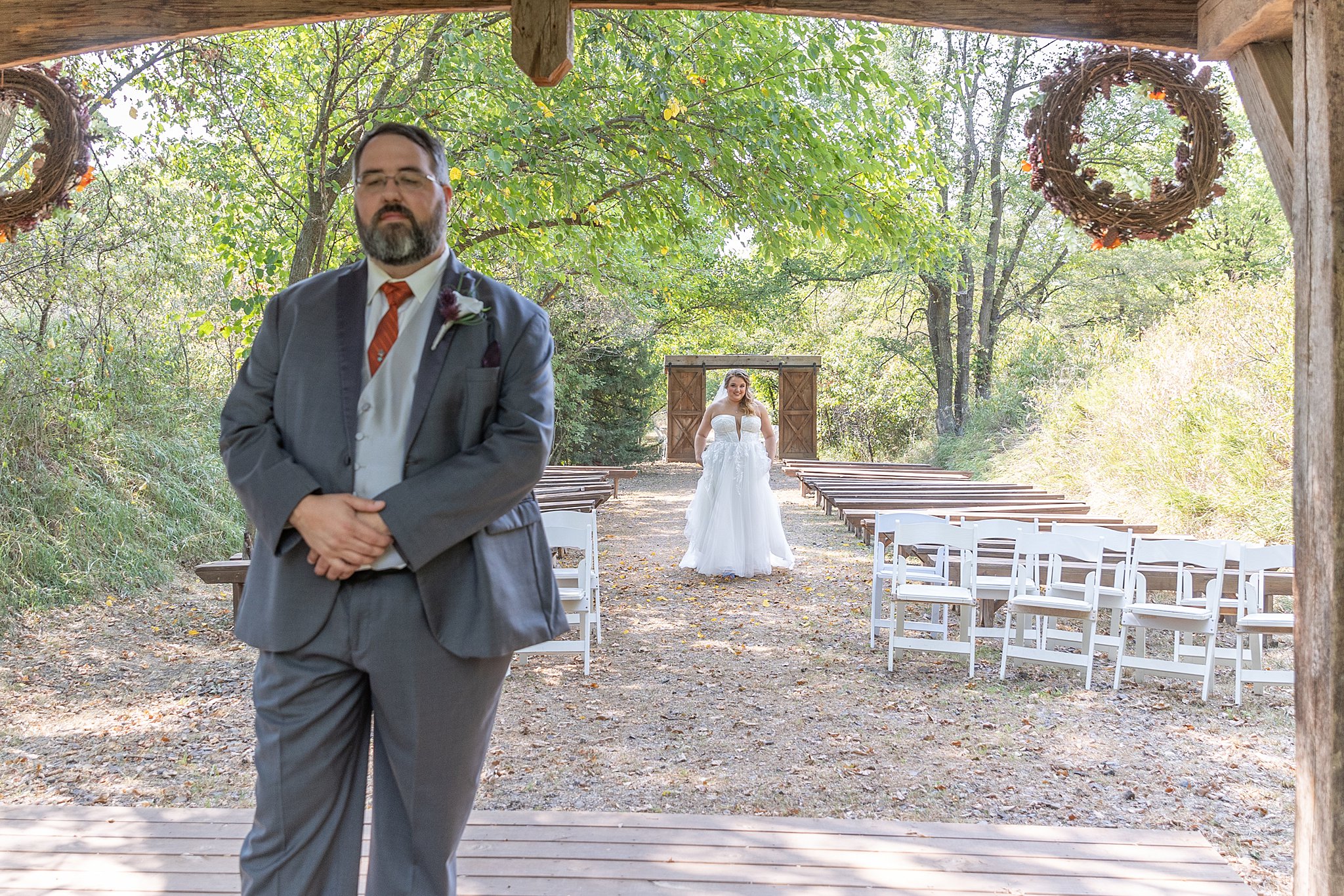 groom stands in a wooden gazebo while bride approaches for first look roca berry farm wedding