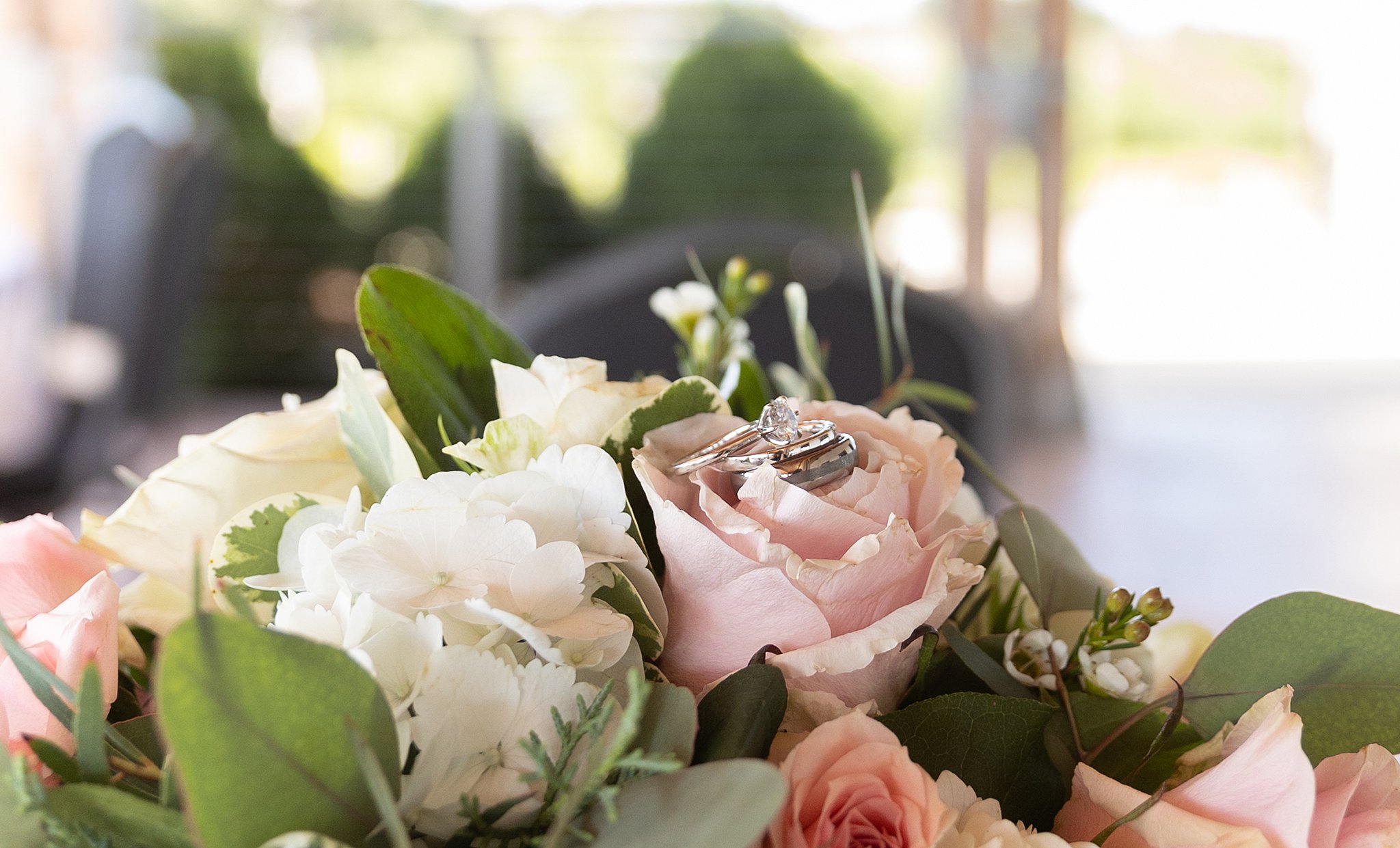 Wedding rings sit on a pink rose of a large bouquet of flowers