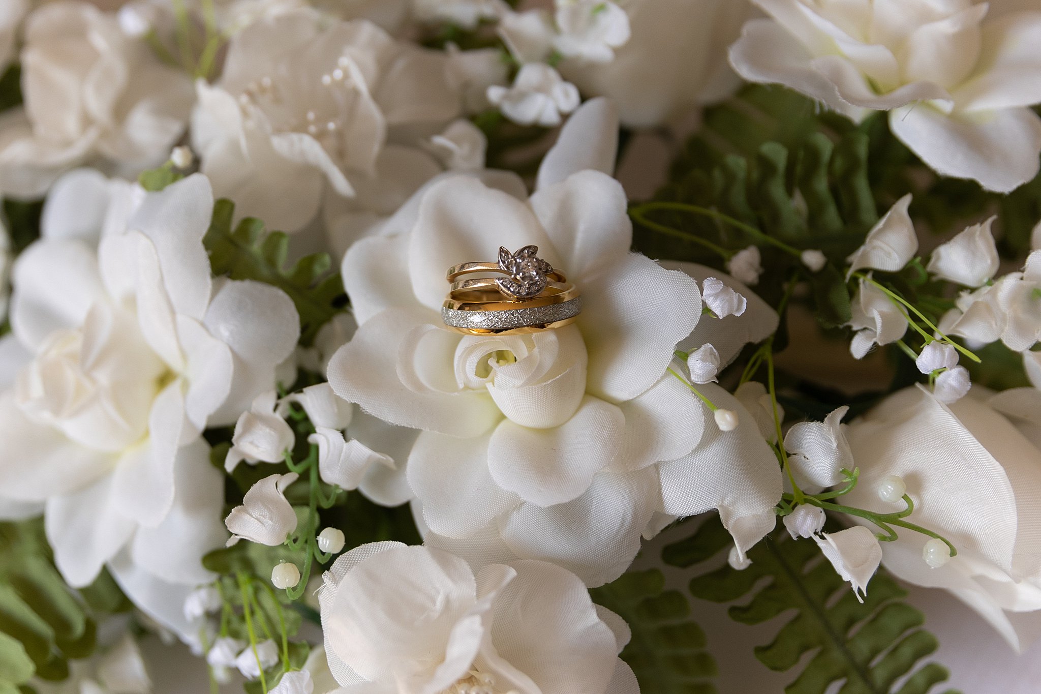 Details of wedding bands sitting on white flowers the omar wedding