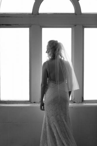 Bride poses in silhouette by a window.