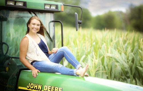 Senior sits on a tractor
