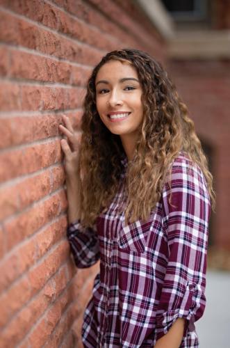 Senior stands by brick wall