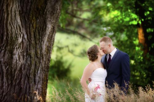 bride and groom kiss by trees