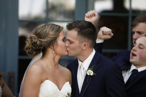 groomsmen celebrate wedding by cheering as bride and groom kiss 