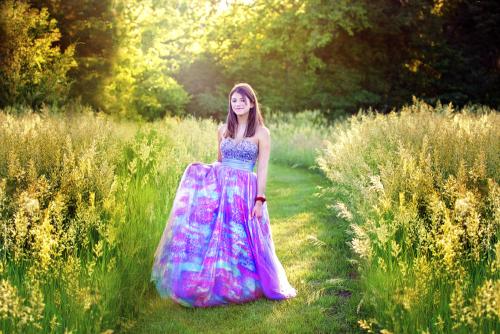 Girl in formal dress walks between tall grass
