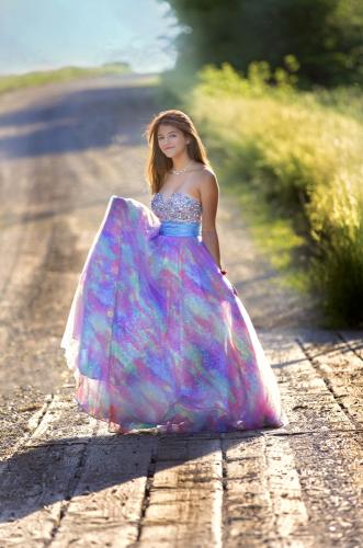 Girl poses on a country road in a blue and purple long dress