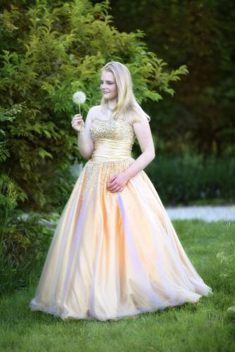 Girl in gold gown looks at fuzzy plant