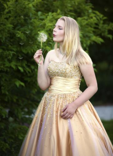 Girl in gold dress blows on plant